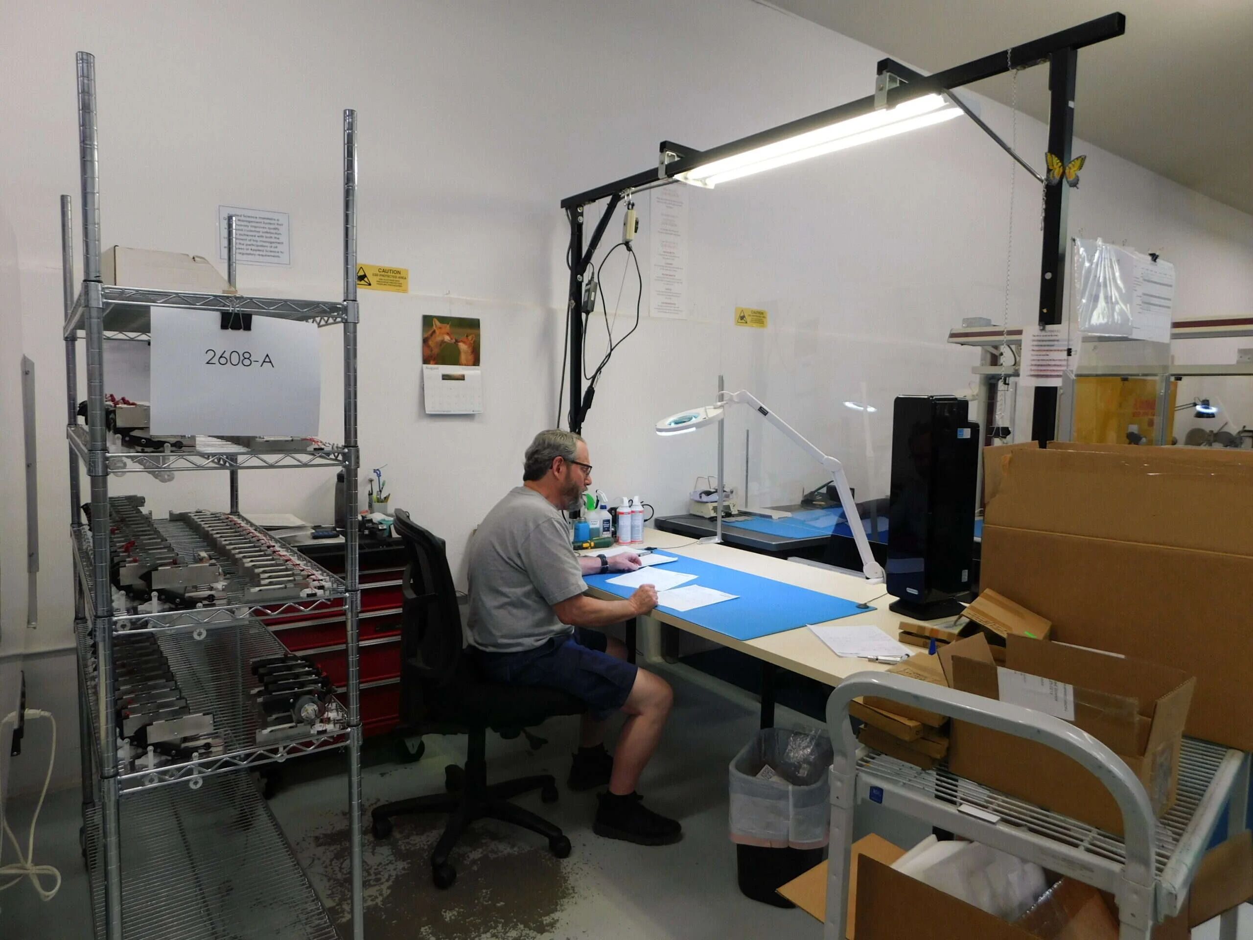 An Applied Science technician assembling HemoFlow boards at a lit bench in Grass Valley