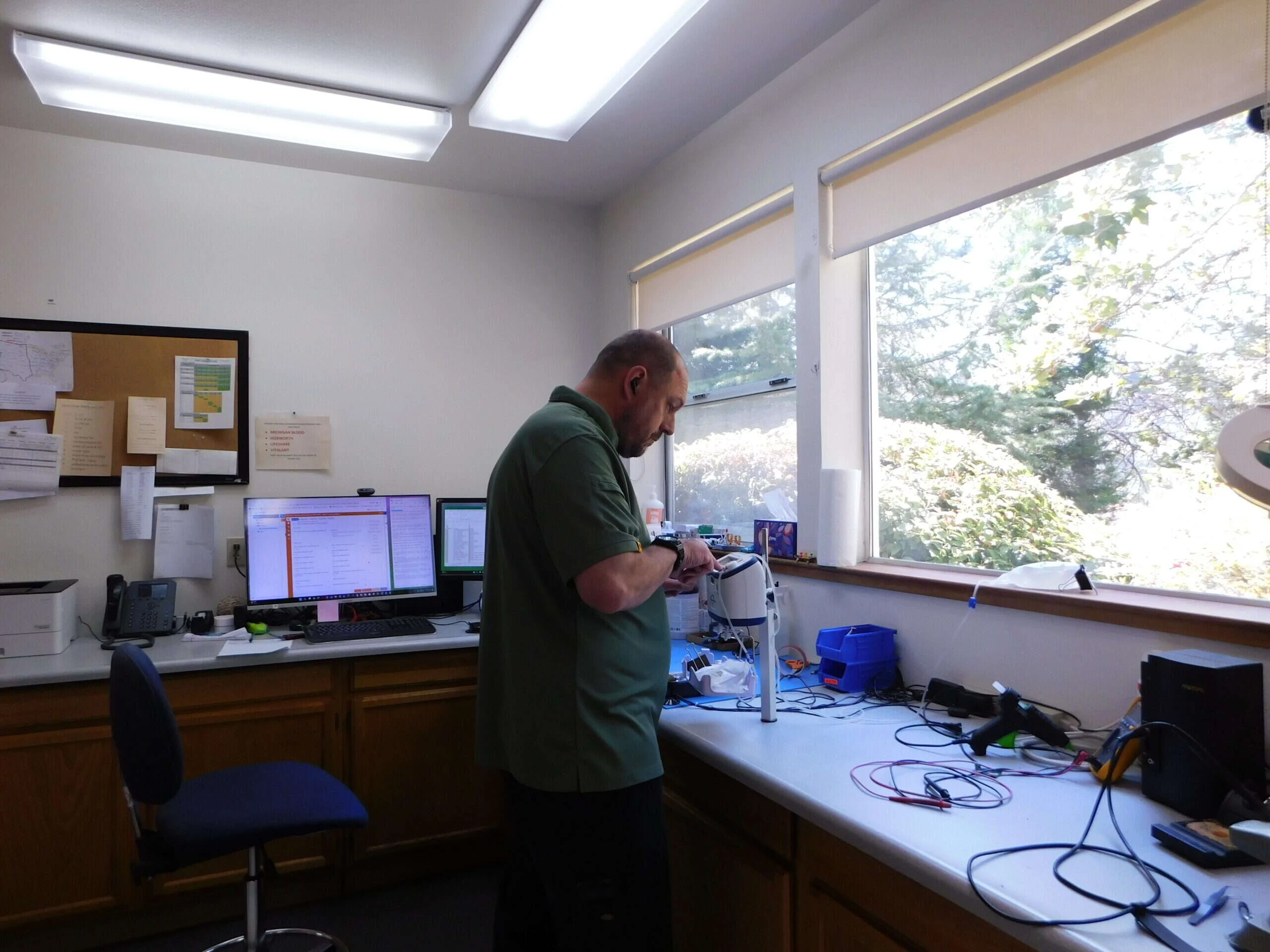 A service technician working on a returned HemoFlow at the daylit repair bench